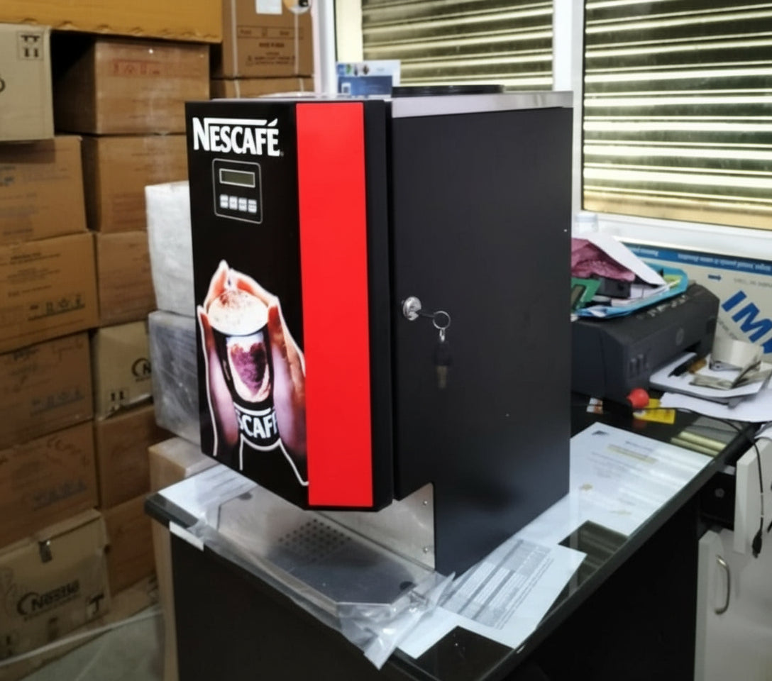 Nescafe 3 lane vending machine Delhi model placed on office desk surrounded by boxes and documents