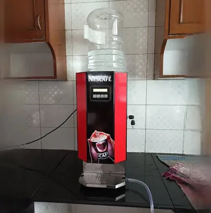 Red and black Nescafe coffee vending machine with water container on top placed on kitchen countertop