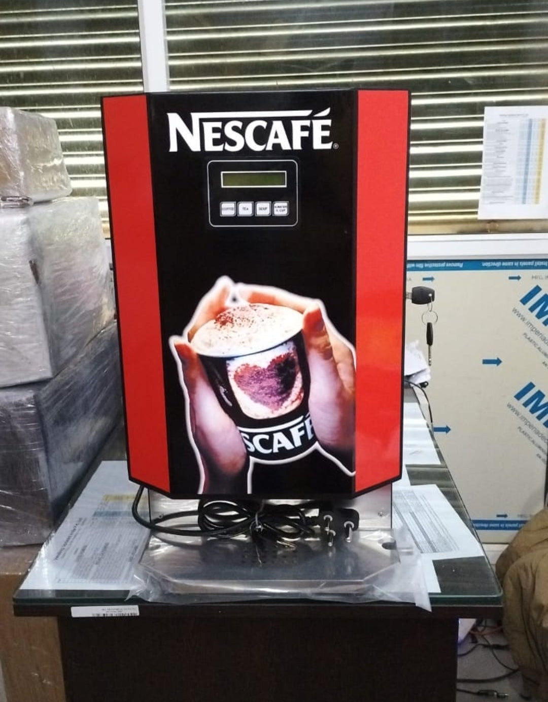 Nescafe smart coffee vending machine in black and red with a digital display and coffee cup graphic