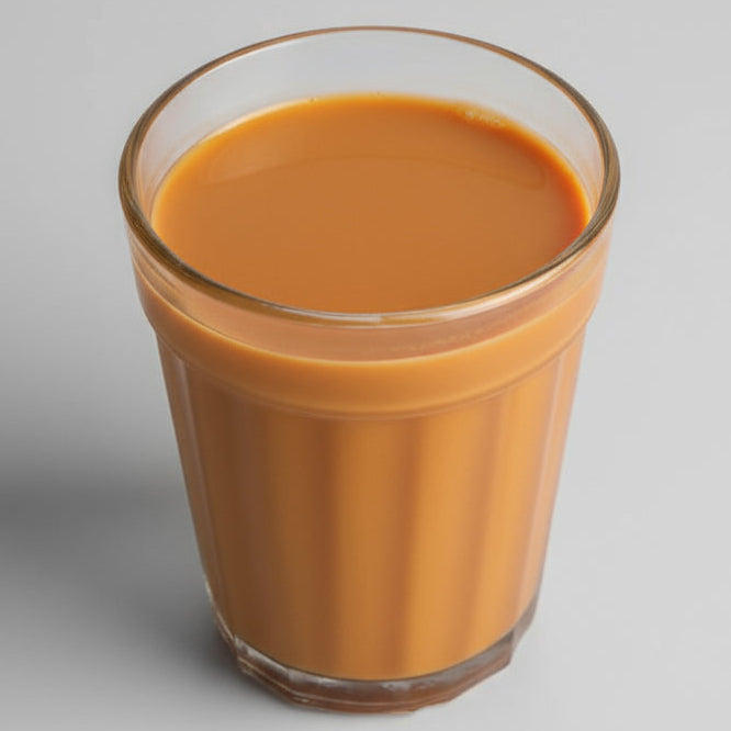 Glass of hot Calcutta Elaichi chai premix tea with a rich creamy texture served on a grey background